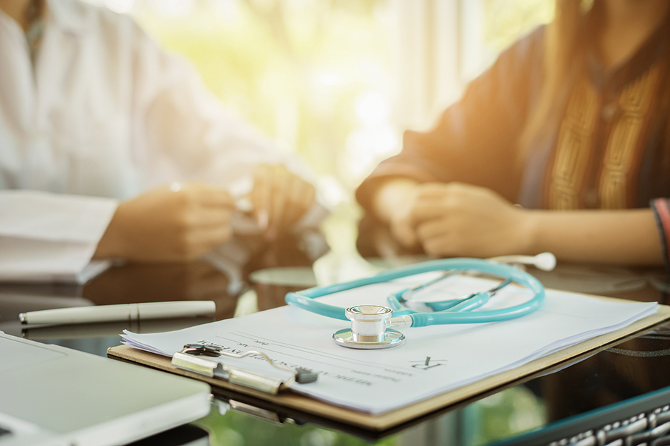 Stethoscope with clipboard and Laptop on desk