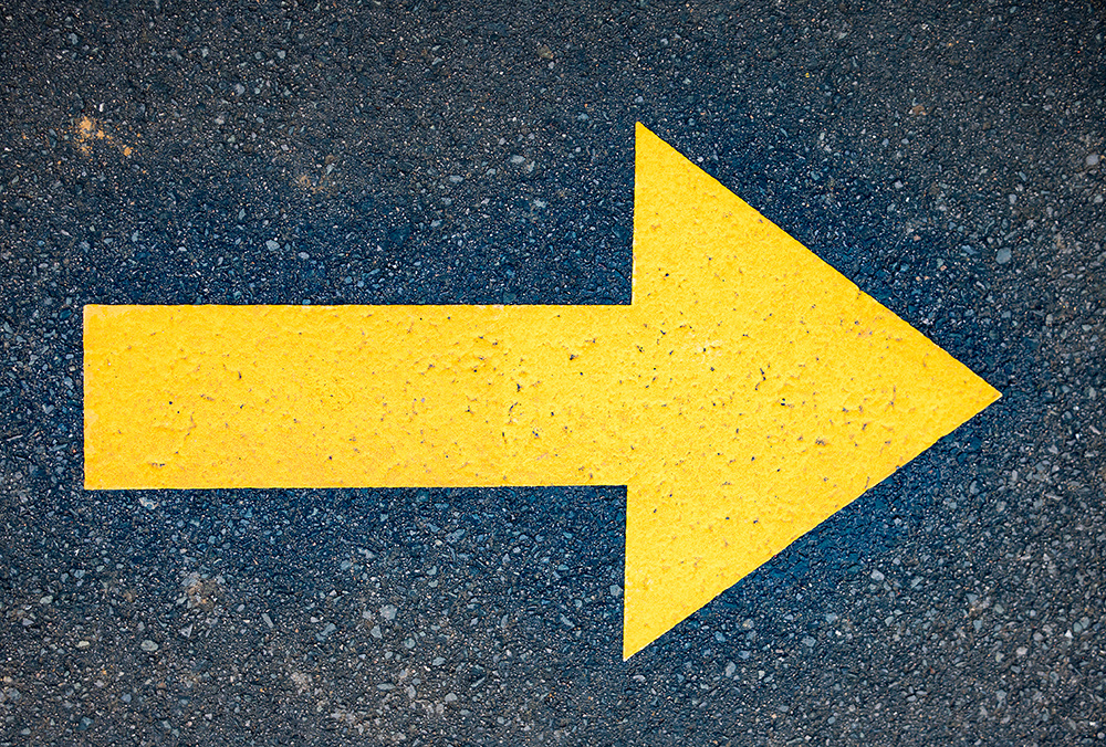 Yellow arrow painted in asphalt road