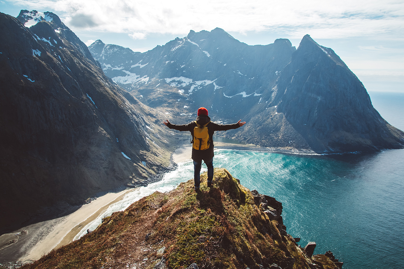 Man stand on cliff edge alone enjoying aerial view backpacking lifestyle travel adventure outdoor vacations